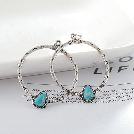 A pair of silver dangle hoop earrings with a turquoise accent