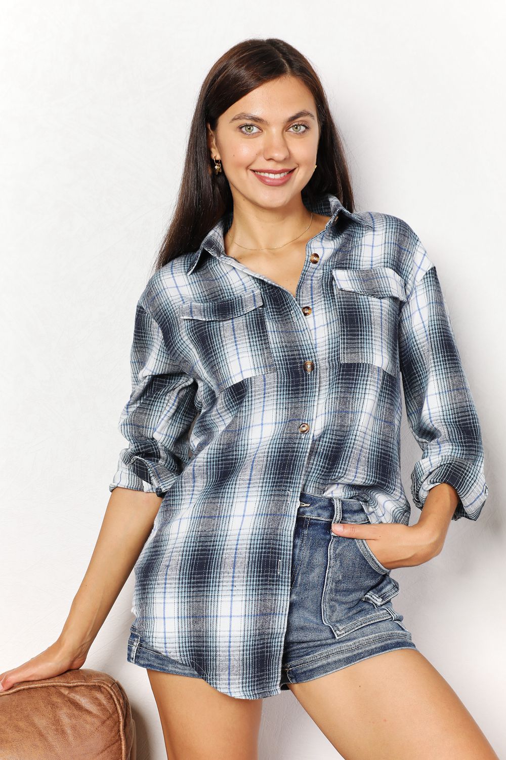 A close shot of a woman wearing a relaxed fit plaid shirt half-tucked into a pair of denim shorts.