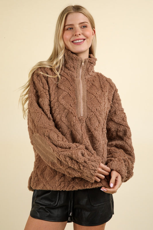 A woman wearing a brown fuzzy cable design pullover fleece with a half zip.