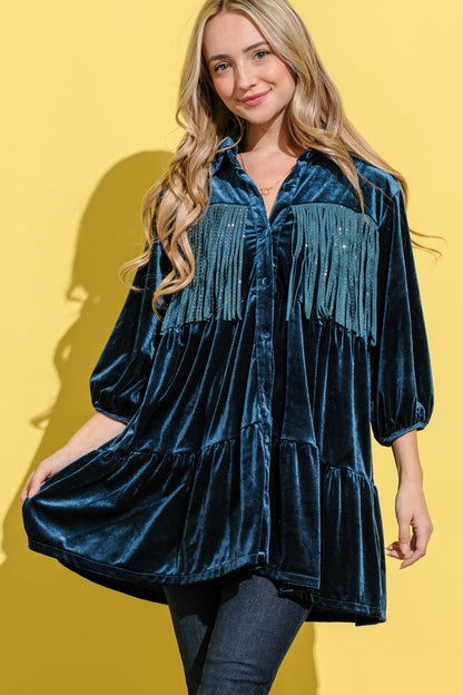 A woman wearing a teal velvet tiered shirt dress tunic blouse with blingy fringe on the front and back. 