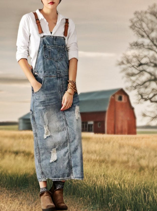 A woman  in a field wearing the distressed denim womens overalls dress.