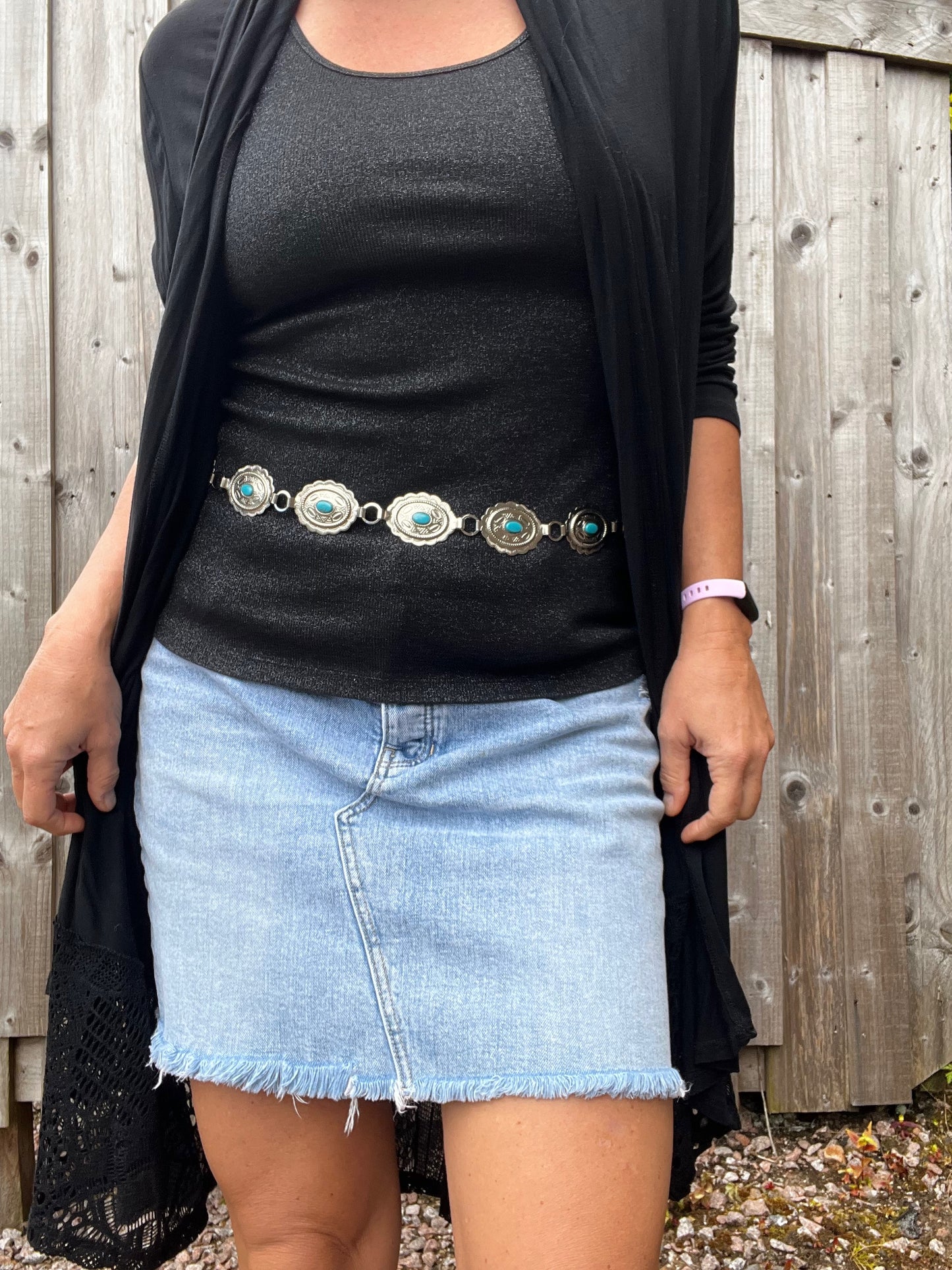 A close shot of a woman wearing a concho belt embellished with turquoise. 