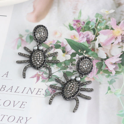 A pair of spider-themed statement earrings, covered in pave rhinestones.