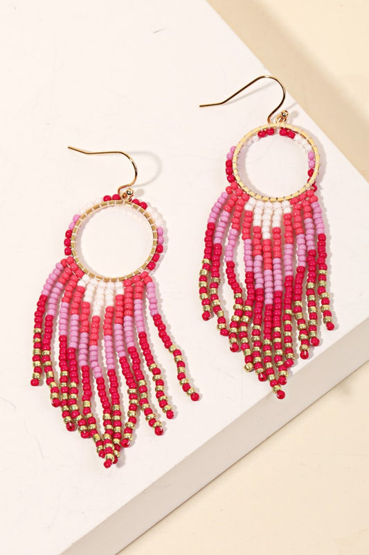 A pair of bright pink dangle earrings made from seed beads.