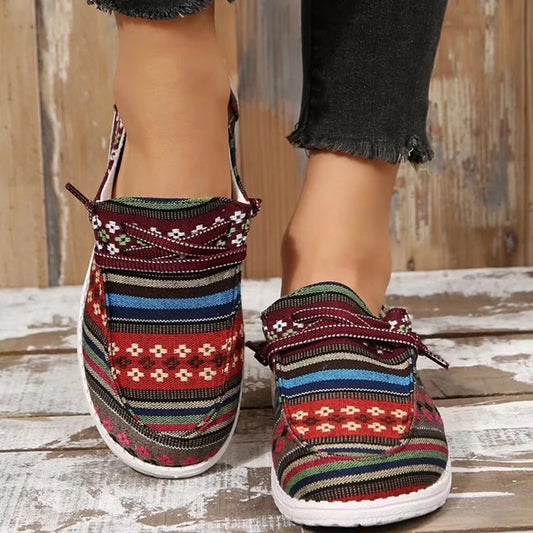 A pair of colorful Western-inspired striped slip-on canvas sneakers against a wooden backdrop.
