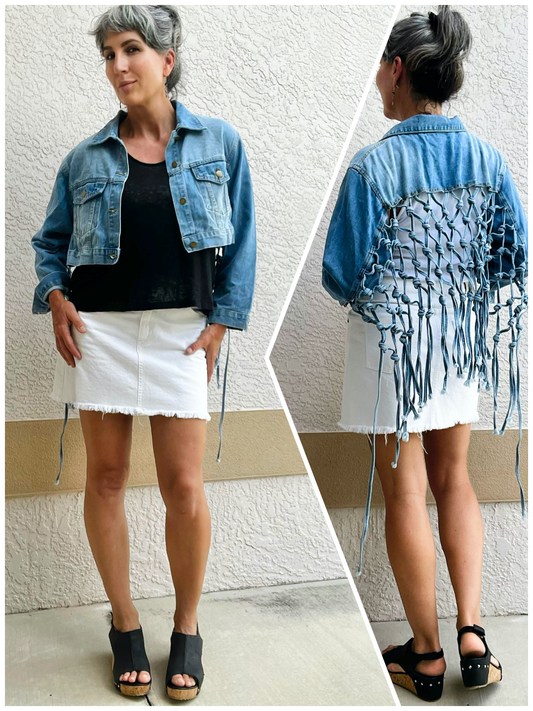 A woman wearing a cropped denim jacket with a woven open back and fringe